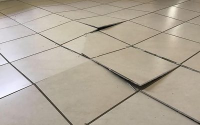 What causes drummy, loose, tenting or peaking tiles?